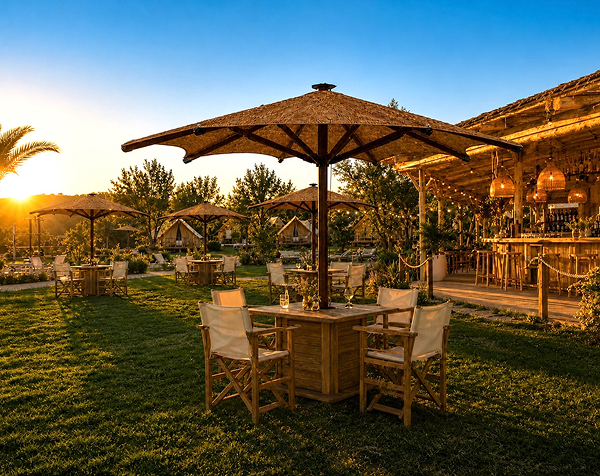 Parasol de exterior con cubierta de fibras naturales y estructura de madera, acompañado de sillas estilo director alrededor de una mesa central en la terraza de un exclusivo restaurante o resort al atardecer.
